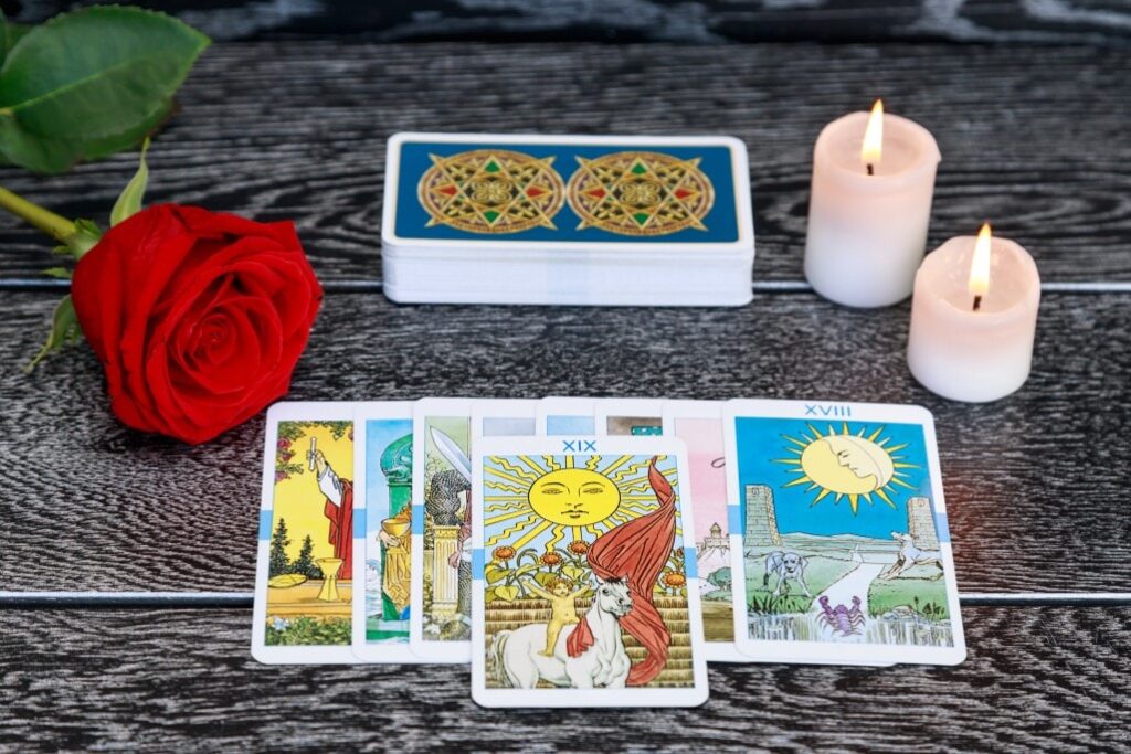 tarot cards scattered on the table a deck of cards burning candles a red rose on a black table t20 roVmJZ min