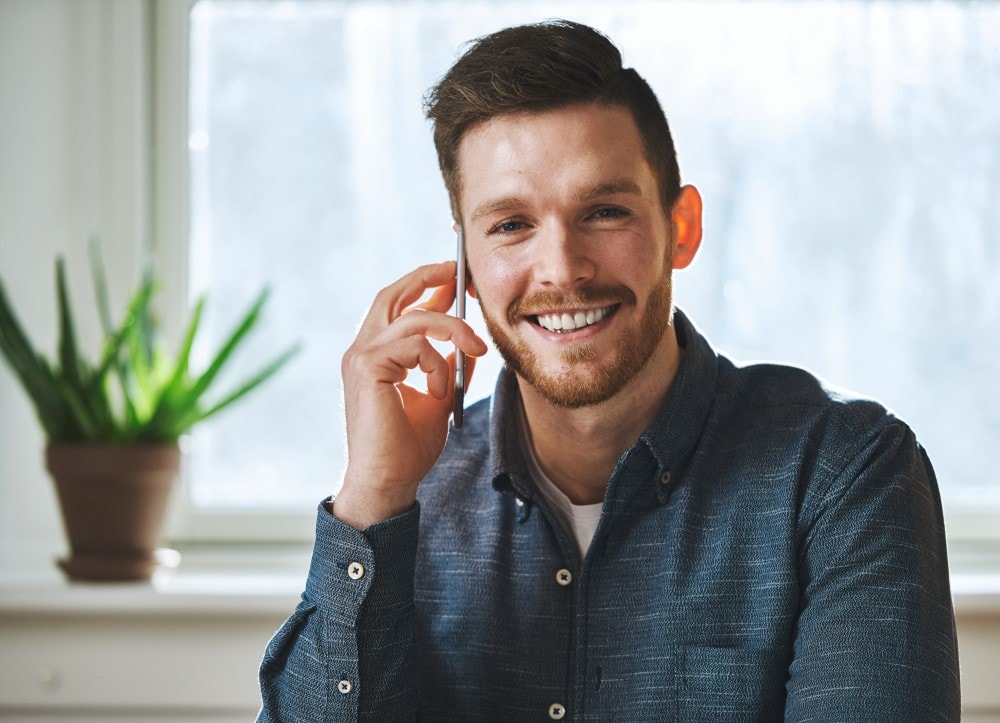 smiling man talking on phone 7YVRQJT min